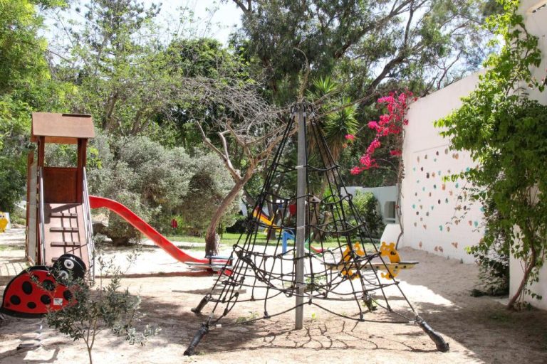 Zona de juegos infantil con tobogán rojo y estructura de escalada en el Hotel Sol Azur
