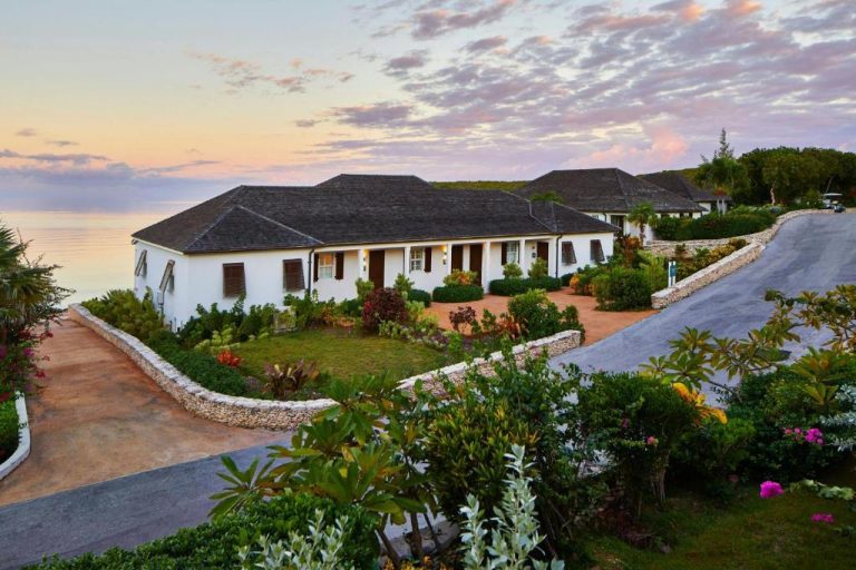 Villa exterior con jardines tropicales y vistas al mar al atardecer en French Leave Resort Autograph Collection