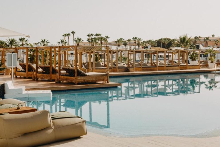 Piscina exterior con cabañas de madera y tumbonas del Lago Resort Menorca Casas del Lago Adults Only