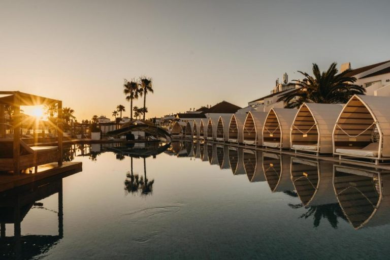 Piscina infinity con cabañas privadas al atardecer en Lago Resort Menorca Casas del Lago Adults Only