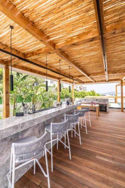 Terraza bar exterior con techo de madera y barra de piedra en Cape Bodrum Luxury Hotel & Beach
