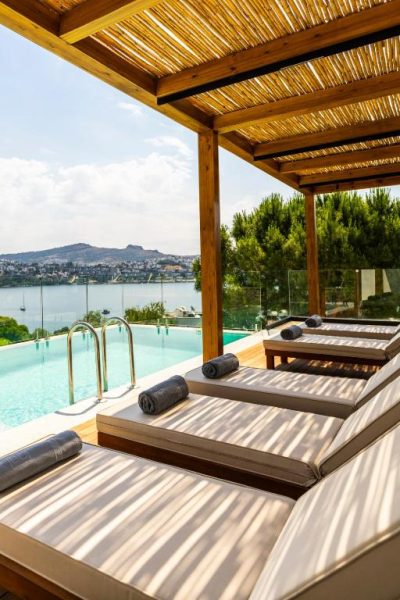 Tumbonas junto a piscina infinita con vistas al mar y montañas en Cape Bodrum Luxury Hotel