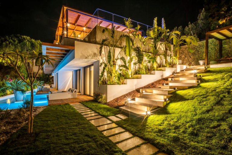 Jardín iluminado con piscina y terrazas tropicales del Cape Bodrum Luxury Hotel de noche