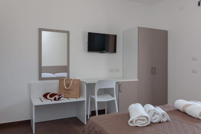 Habitación doble con escritorio, espejo y TV del Resort La Ficaccia en Cerdeña
