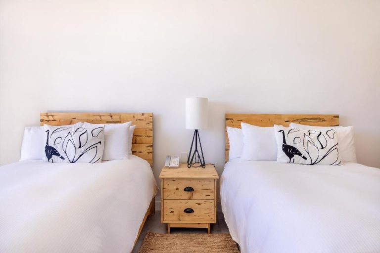 Habitación doble con dos camas y cabeceros de madera rústica en Hotel El Ganzo Adults Only