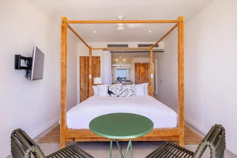 Habitación con cama de dosel de madera y decoración minimalista en Hotel El Ganzo Adults Only