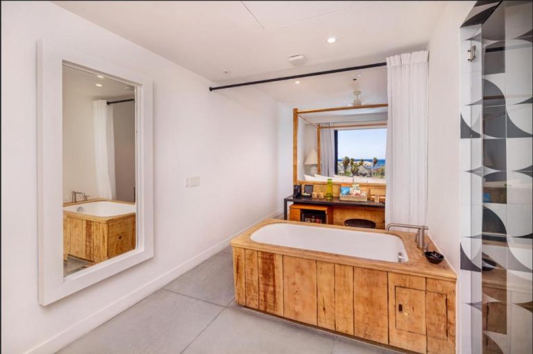 Lujosa bañera exenta con encimera de madera en suite del Hotel El Ganzo Adults Only con vistas al mar