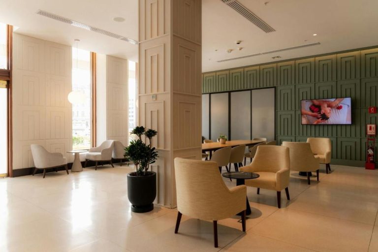 Elegante lobby lounge con sillones beige y pared verde del Sheraton Lima Historic Center