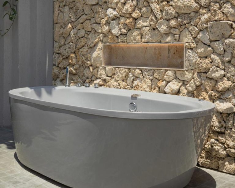 Bañera exenta de diseño con pared de piedra natural en el spa exterior del Osh Hotel Cartagena