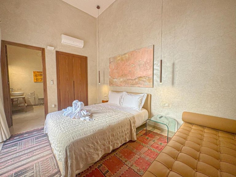 Habitación doble con decoración marroquí y toallas decoradas en la cama del Riad Timija
