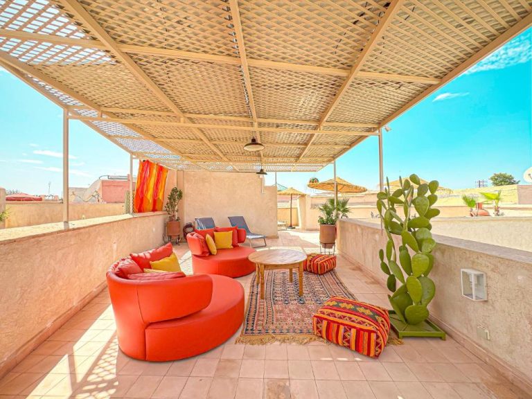Terraza exterior con sofás rojos y decoración bereber del Riad Timija en Marrakech