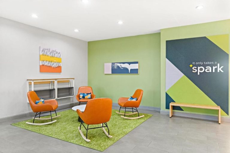 Zona lounge con sillas mecedoras naranjas y decoración moderna en Spark by Hilton Panama City Beach