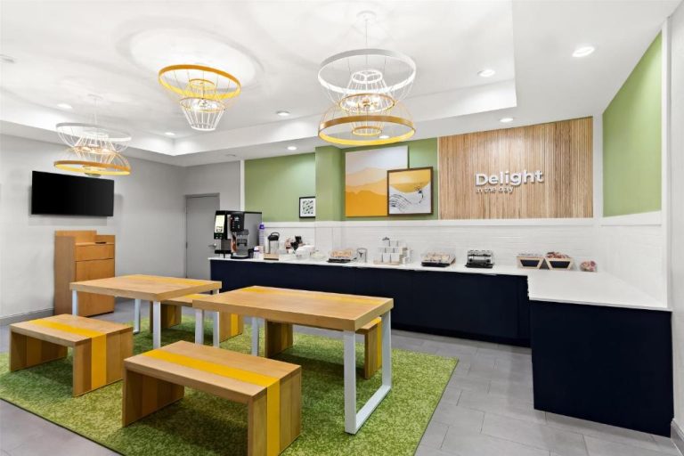 Zona de desayuno buffet del Spark by Hilton Panama City Beach con mesas de madera y barra de servicio