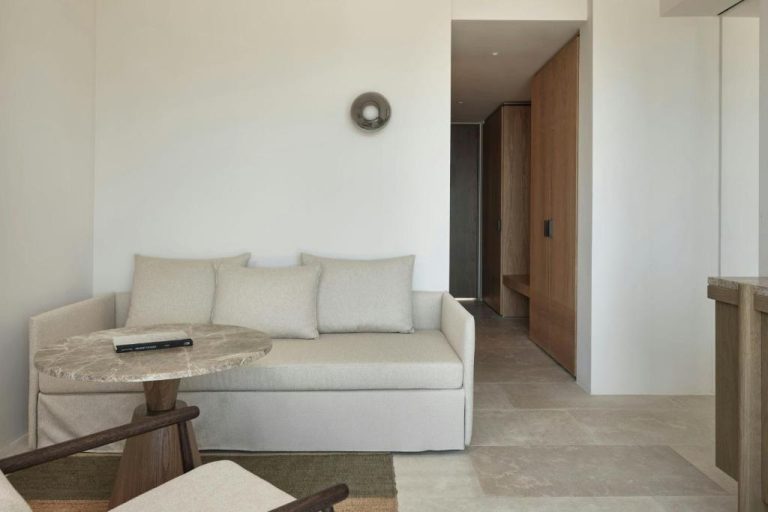Salón minimalista con sofá beige y mesa de mármol en suite del JW Marriott Crete Resort & Spa