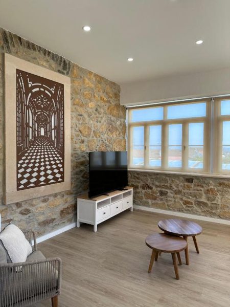 Salón con pared de piedra natural, TV y decoración artística en Palacium Charming Suites