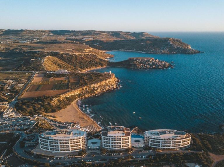 Vista aérea del Radisson Blu Resort & Spa Malta Golden Sands con playa y acantilados al atardecer