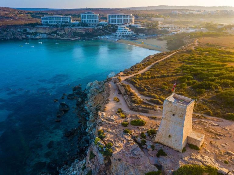 Vista aérea del Radisson Blu Resort & Spa Malta Golden Sands con torre costera y bahía de aguas turquesas