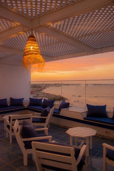 Terraza con sofás azules y vistas al mar al atardecer en el Hôtel Al Jazira Mahdia