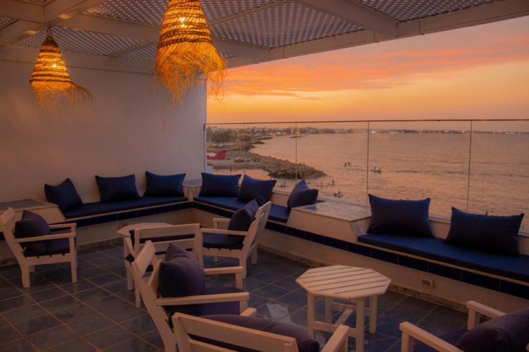 Terraza lounge con sofás azules y vistas al mar al atardecer en el Hôtel Al Jazira Mahdia
