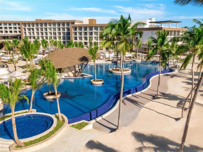 Piscina exterior con bar acuático y palmeras del Hyatt Ziva Cap Cana en República Dominicana