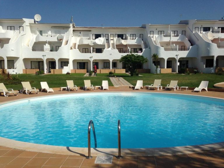 Piscina exterior circular con tumbonas blancas y edificio principal del Hotel Vilamar en el Algarve