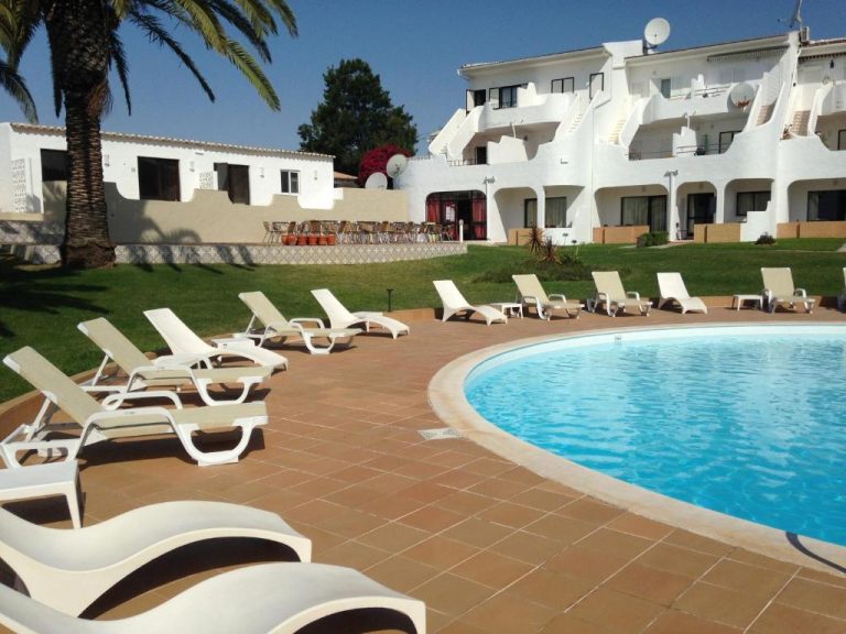 Piscina exterior con tumbonas blancas y jardín del Hotel Vilamar en el Algarve, Portugal