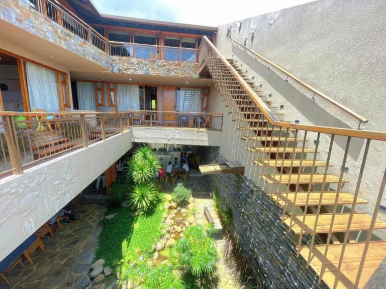 Patio interior con jardín tropical y escaleras de madera del MăngDiang Boutique Hotel