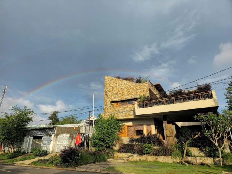Fachada exterior de piedra del MăngDiang Boutique Hotel con arcoíris en el cielo de Vietnam