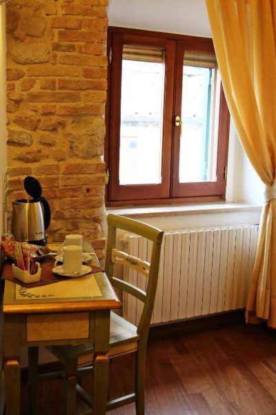 Rincón de desayuno con mesa de madera y hervidor en Primavera Mini Hotel con pared de piedra