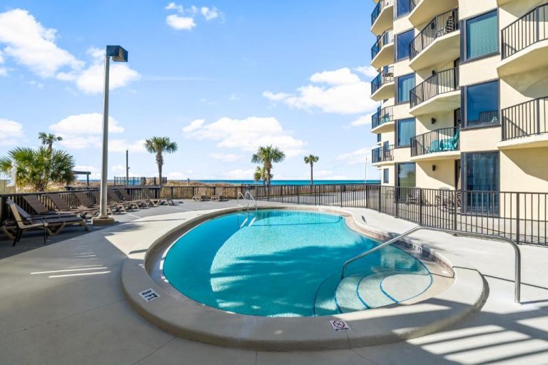 Piscina exterior redonda con vistas al mar en Sunbird of Panama City Beach, rodeada de palmeras