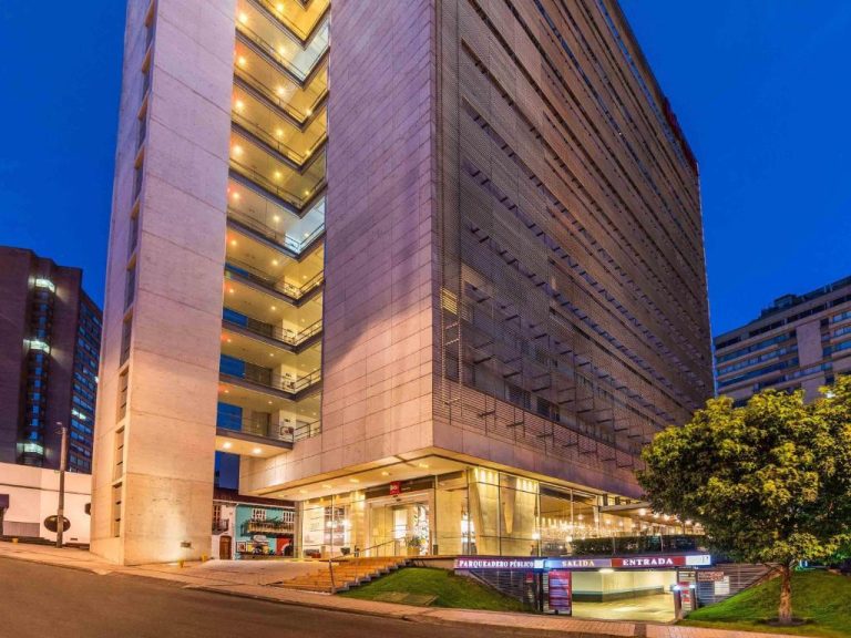 Fachada exterior nocturna del Hotel ibis Bogotá Museo con entrada y parqueadero público iluminado