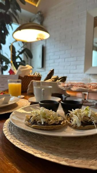 Desayuno con tostadas de frijoles y col en Casa Pani, servido con jugo de naranja y café
