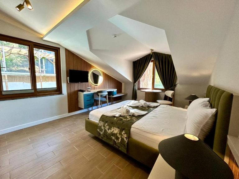 Habitación abuhardillada con cama doble verde y escritorio azul en Castello by Mediterra Hotel