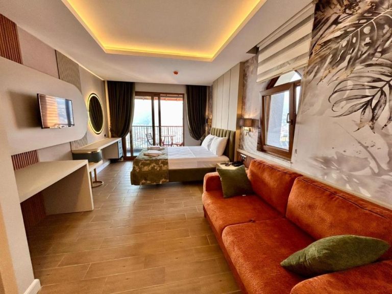 Suite amplia con sofá naranja, cama doble y terraza con vistas en Castello by Mediterra Hotel