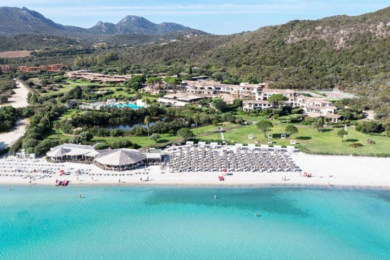 Vista aérea del Hotel Abi d'Oru con playa de aguas turquesas y tumbonas en Cerdeña