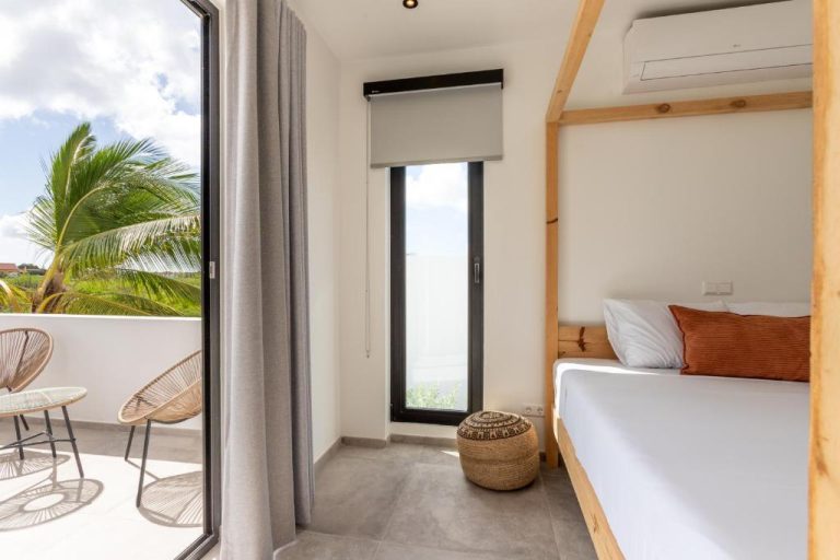 Habitación doble con cama de madera, balcón privado y vistas a palmeras en Luxury Villa