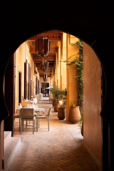Corredor exterior con mesas del restaurante del hotel Les Jardins de la Koutoubia en Marrakech