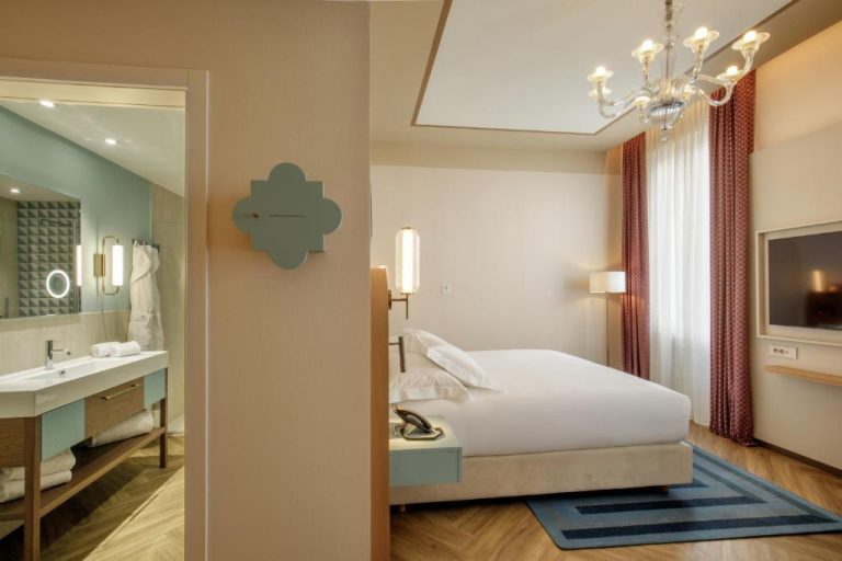 Habitación superior con cama doble, lámpara de araña y baño en suite del Rosetta Hotel Perugia Hilton