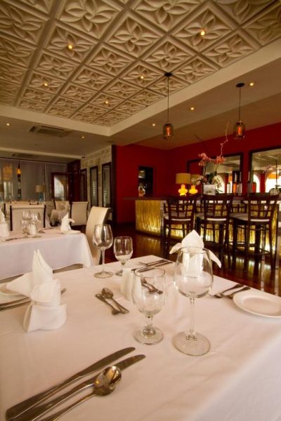 Elegante restaurante del S Hotel Kingston con mesas blancas, copas de vino y techo decorativo en relieve