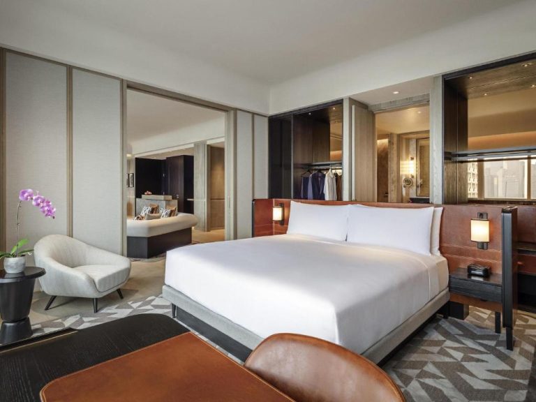 Suite de lujo con cama king size y vestidor en el Fairmont Singapore con diseño elegante