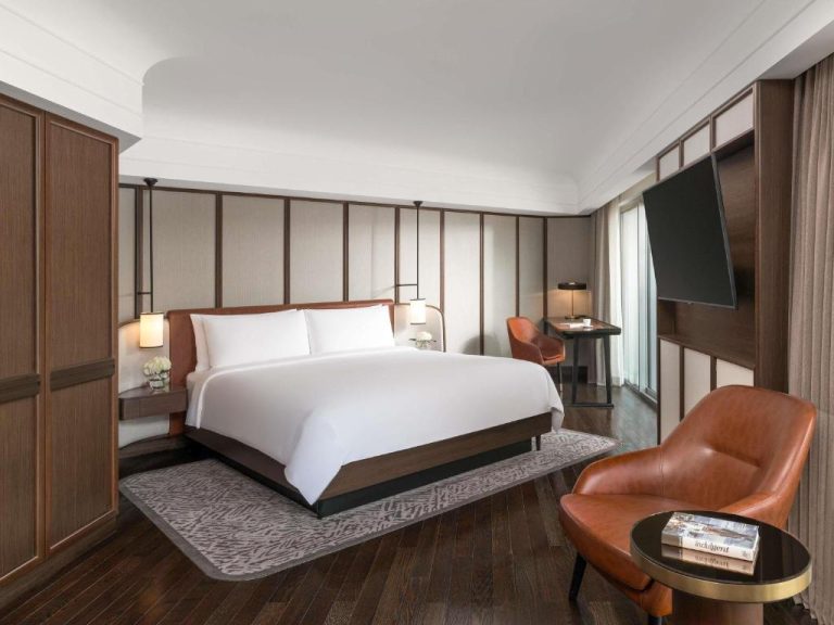 Habitación King Deluxe con cama doble, suelos de madera y decoración elegante en Fairmont Singapore