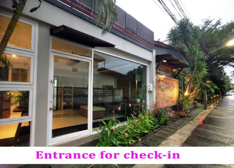 Entrada principal y zona de check-in del hotel Cafe Luv22 con jardín tropical y fachada acristalada
