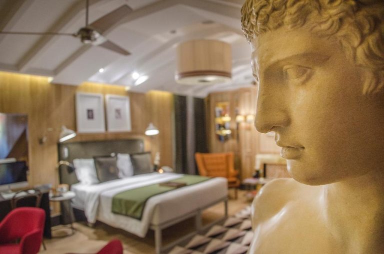 Habitación de lujo del Browns Central Hotel decorada con escultura clásica grecorromana y cama doble