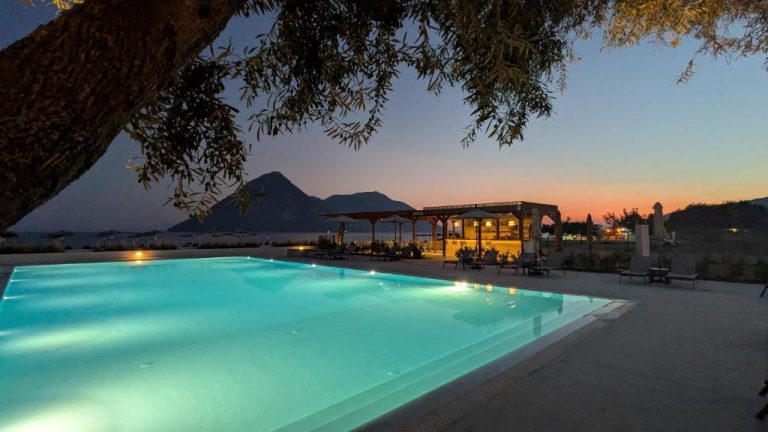 Piscina iluminada al atardecer con vistas al mar en el Costa Ionica Mytikas Seaside Hotel