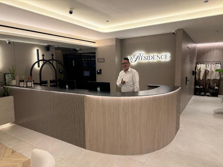 Recepción moderna del hotel La Residence Panamá con mostrador de madera iluminado y personal atendiendo