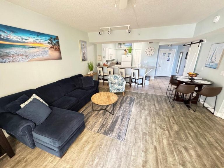 Sala de estar con sofá azul y cocina abierta en el apartamento Shores of Panama 315 en Panama City Beach