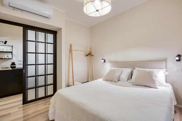 Habitación doble con cama matrimonial blanca y puerta corredera en WelcHome Wellness Suites