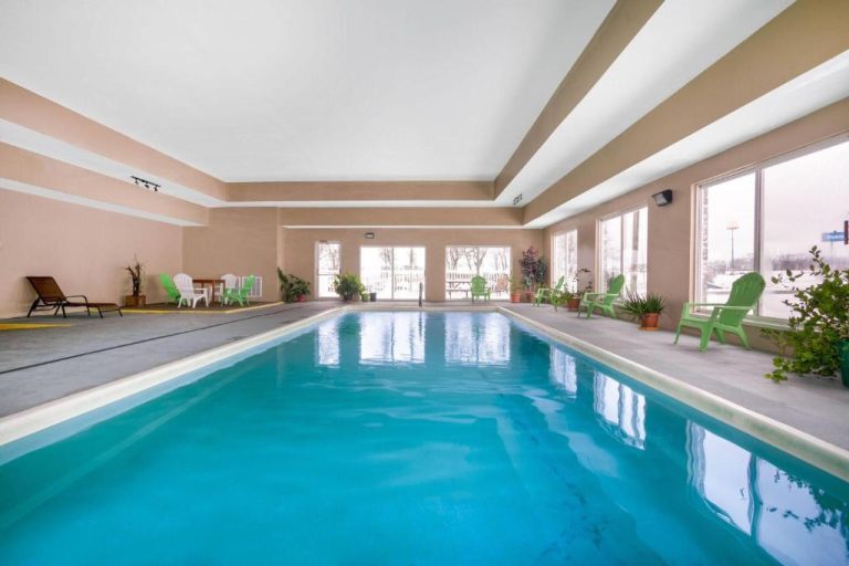Piscina interior climatizada del Days Inn & Suites by Wyndham Cuba con tumbonas verdes y grandes ventanales