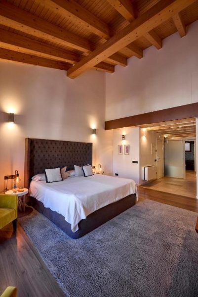 Habitación superior con cama doble, techo de vigas de madera y suelo de parqué en Hotel Bosch Boutique