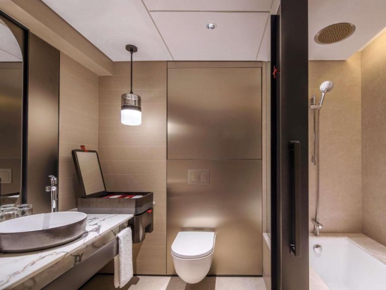 Baño de lujo con bañera, ducha y lavabo de mármol en el Swissotel The Stamford Singapore
